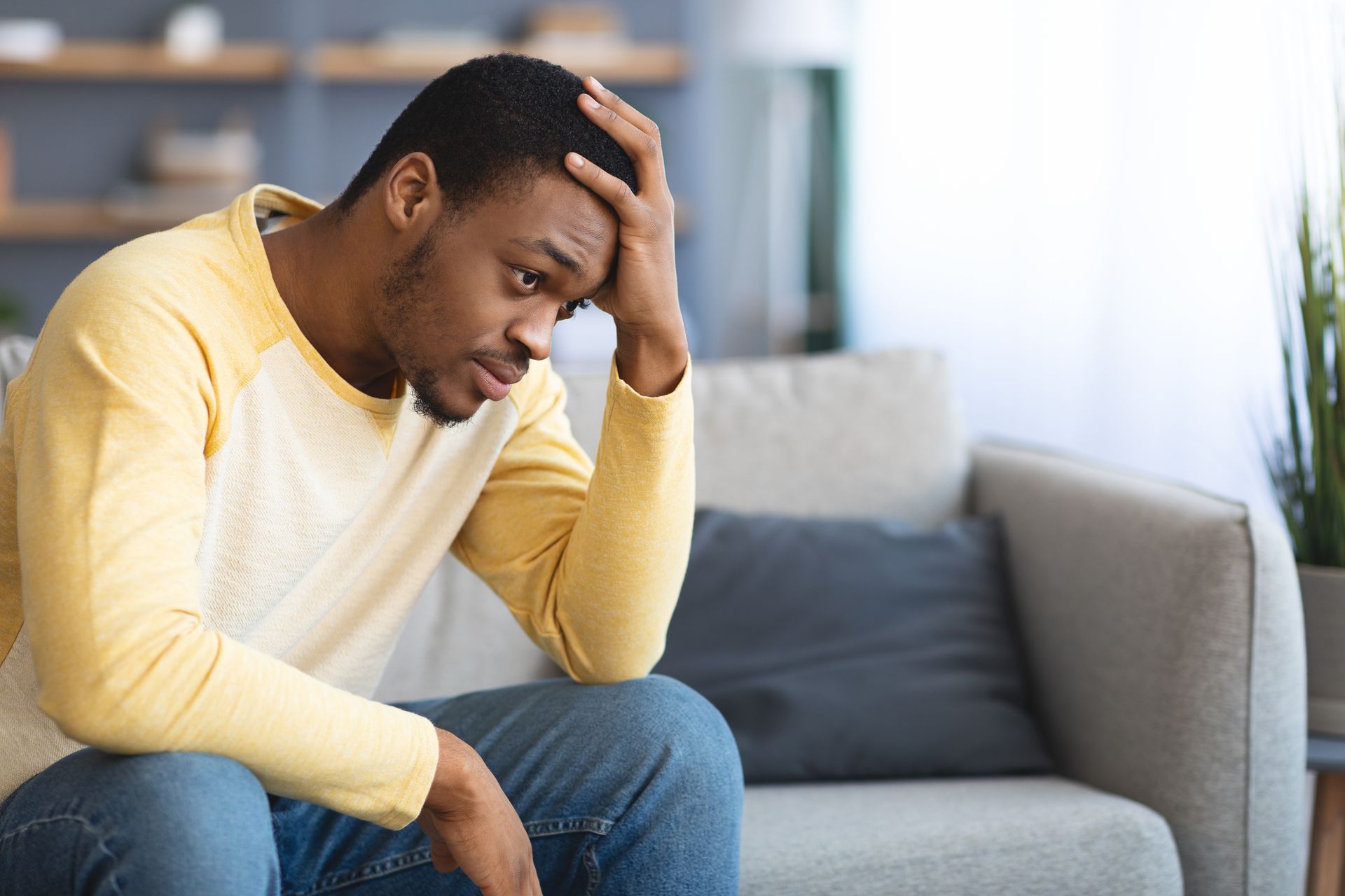frustrated young black man sitting on couch in liv 2021 09 02 07 18 16 utc